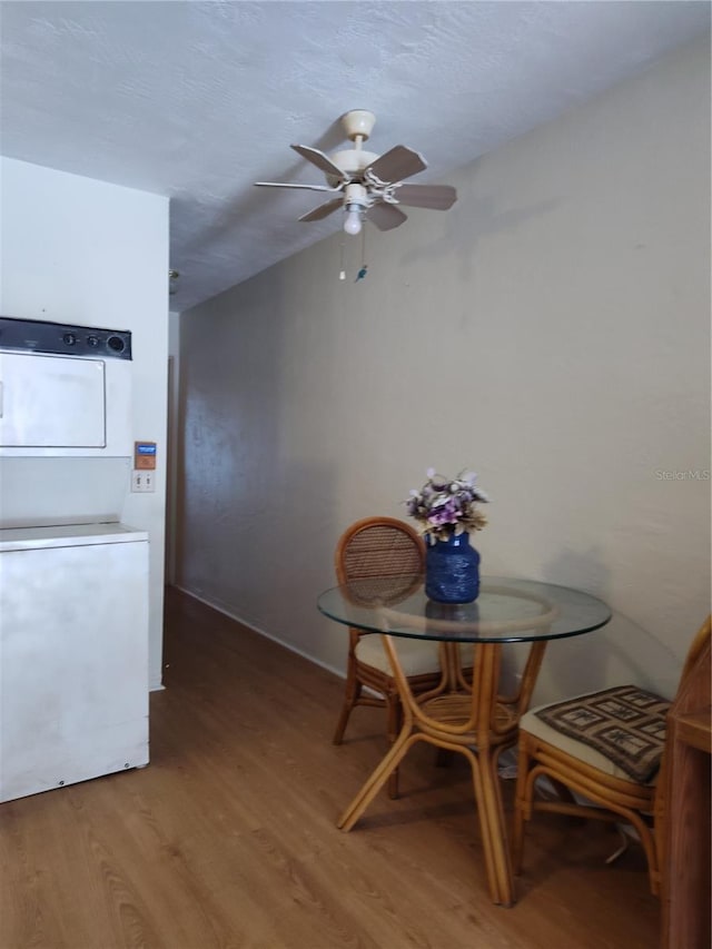 dining room with hardwood / wood-style flooring, ceiling fan, and stacked washing maching and dryer