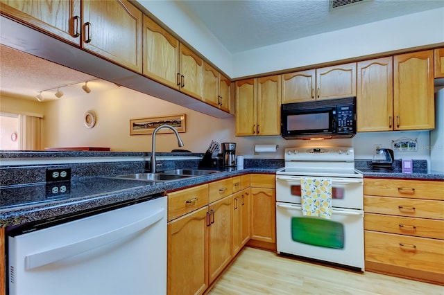 kitchen with sink, a textured ceiling, light wood-type flooring, white appliances, and dark stone counters