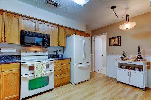 kitchen with decorative light fixtures, white appliances, and light hardwood / wood-style floors