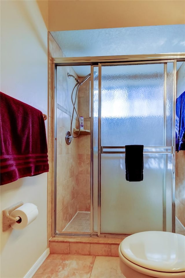 bathroom with tile patterned floors, toilet, and an enclosed shower