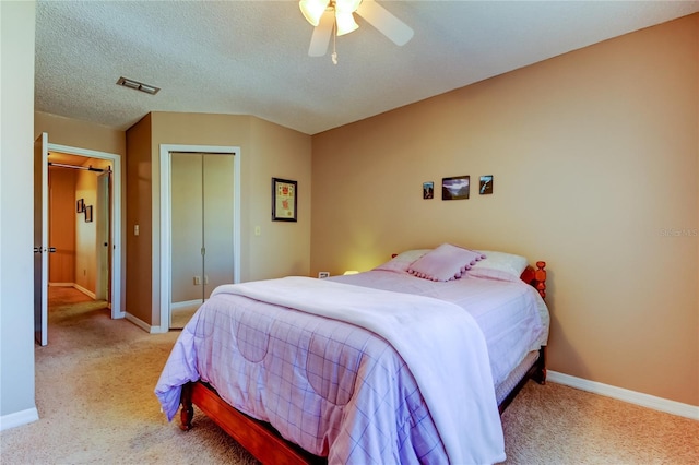 carpeted bedroom with ceiling fan, a closet, and a textured ceiling