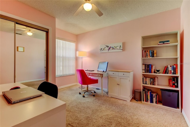 carpeted home office featuring a textured ceiling and ceiling fan