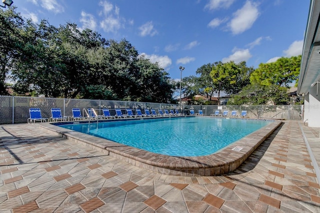 pool with a patio area and fence