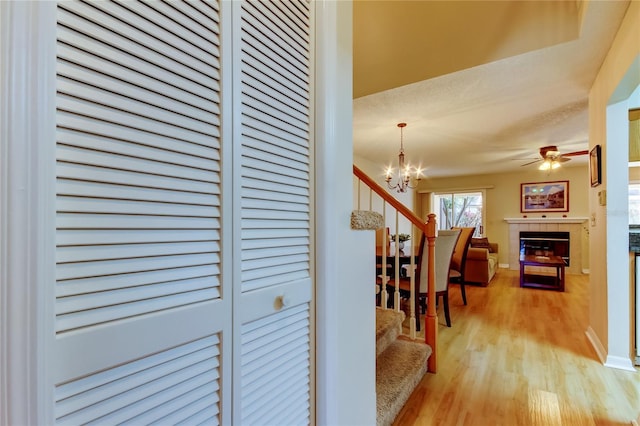 hallway with baseboards, a notable chandelier, light wood-style flooring, and stairs