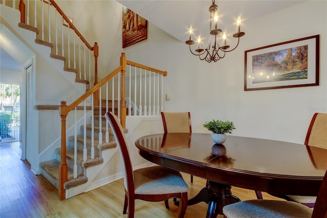 dining space with a notable chandelier, wood finished floors, and stairs