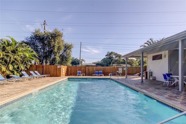 community pool with a patio area and a fenced backyard