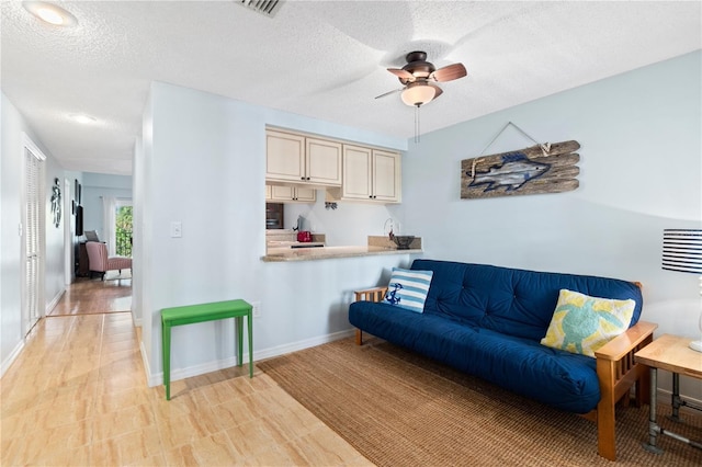 living room with ceiling fan and a textured ceiling