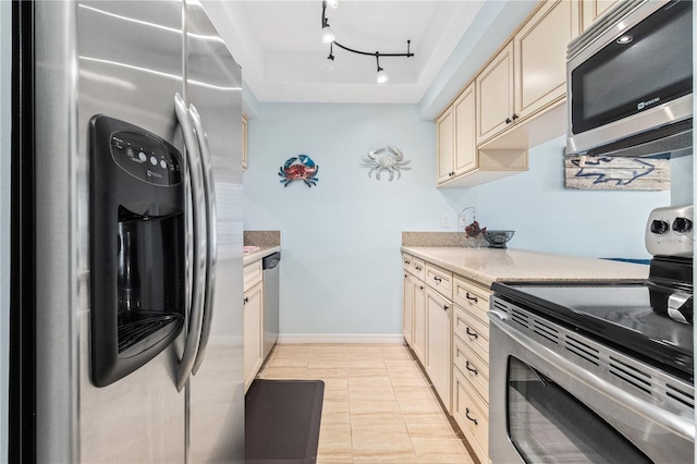 kitchen featuring rail lighting, appliances with stainless steel finishes, light tile patterned floors, and cream cabinets