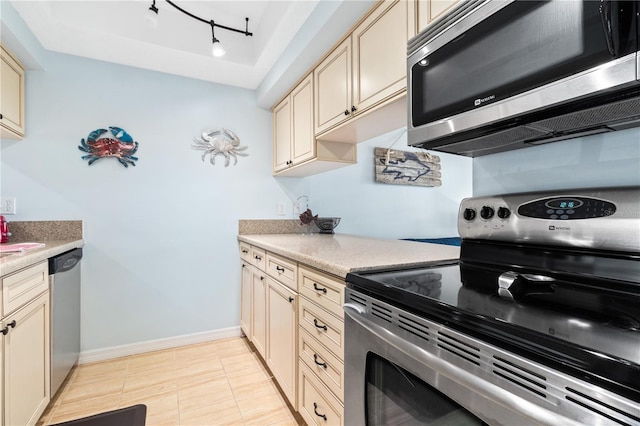 kitchen featuring appliances with stainless steel finishes, track lighting, and cream cabinets