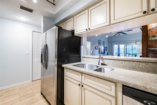 kitchen featuring light stone counters, cream cabinets, sink, and appliances with stainless steel finishes