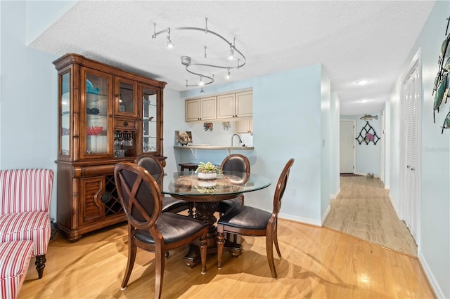 dining space featuring a textured ceiling and light hardwood / wood-style flooring