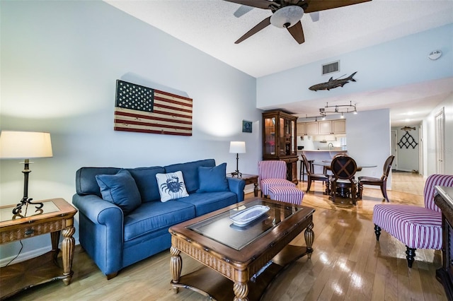 living room featuring a textured ceiling, track lighting, light hardwood / wood-style floors, and ceiling fan