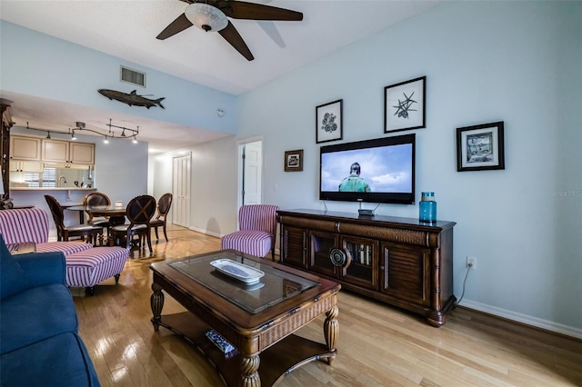 living room featuring rail lighting, ceiling fan, and light hardwood / wood-style flooring