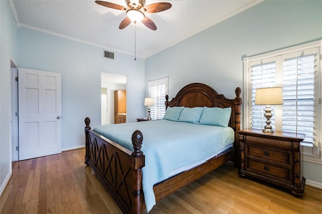 bedroom with hardwood / wood-style flooring, ornamental molding, and multiple windows