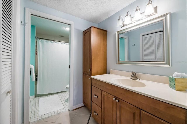 bathroom with tile patterned floors, vanity, toilet, and a textured ceiling