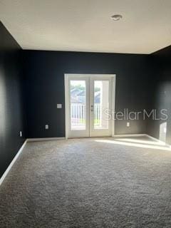 carpeted spare room featuring french doors