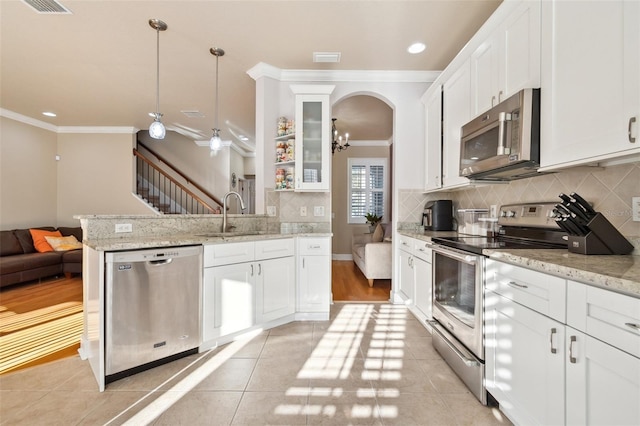 kitchen featuring stainless steel appliances, decorative light fixtures, and white cabinets