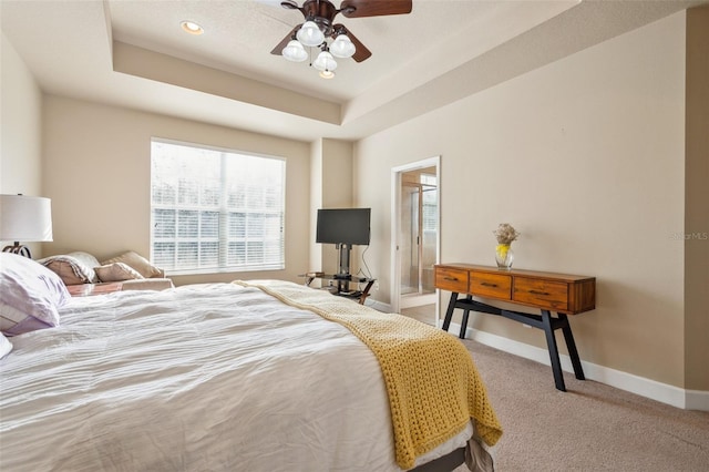 carpeted bedroom with ceiling fan and a raised ceiling