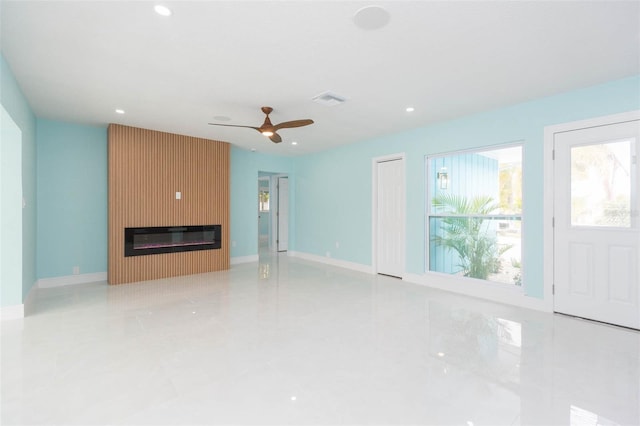 unfurnished living room with a large fireplace and ceiling fan