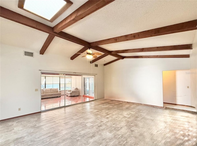 unfurnished living room featuring lofted ceiling with beams, ceiling fan, hardwood / wood-style floors, and a textured ceiling