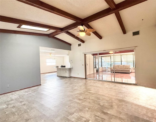 unfurnished living room featuring lofted ceiling with beams, ceiling fan, and a textured ceiling