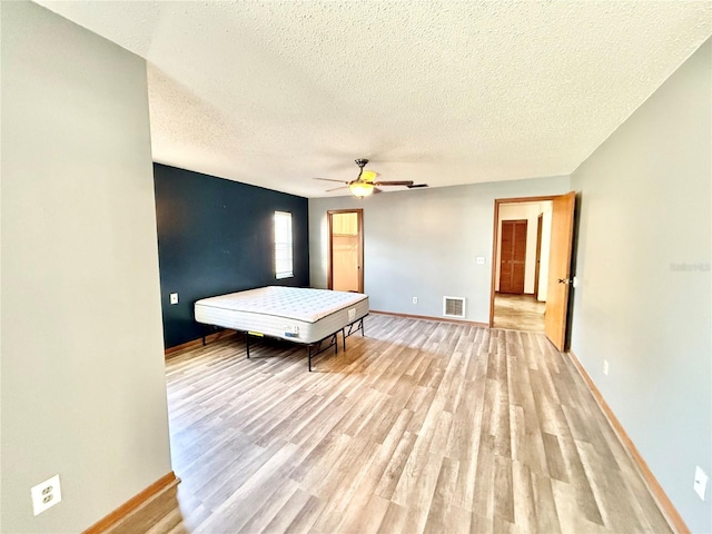 unfurnished bedroom with ceiling fan, a textured ceiling, and light wood-type flooring