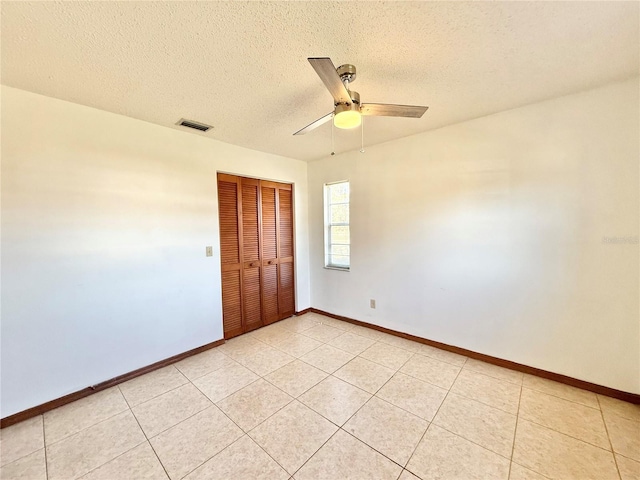 tiled spare room with ceiling fan and a textured ceiling