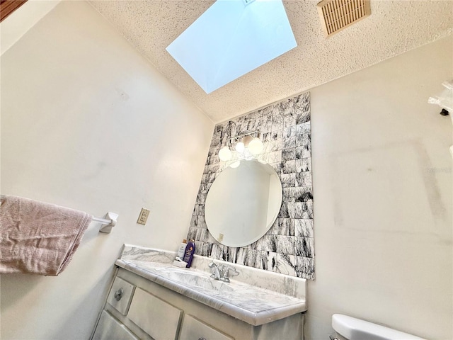 bathroom featuring vanity, lofted ceiling with skylight, and toilet