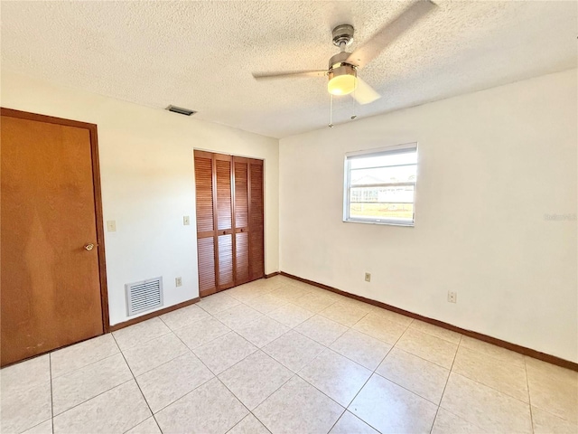 unfurnished bedroom featuring ceiling fan, a closet, a textured ceiling, and light tile patterned flooring