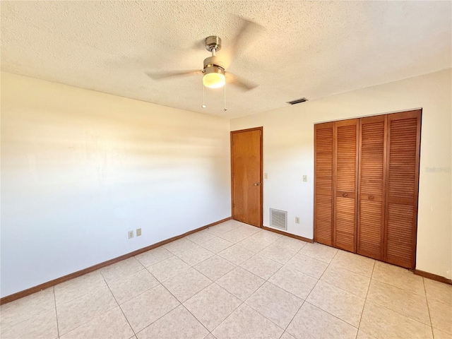 unfurnished bedroom with ceiling fan, light tile patterned floors, a closet, and a textured ceiling