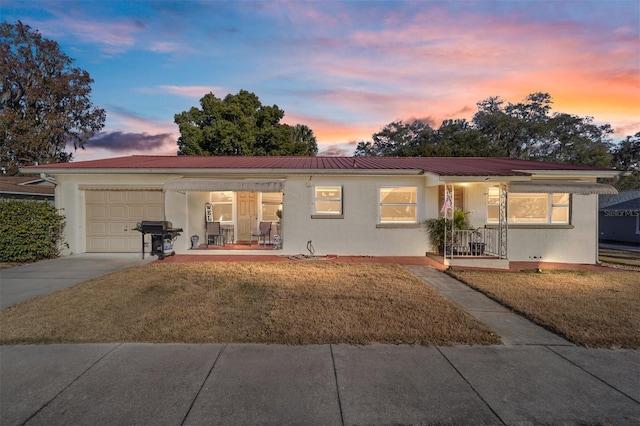 ranch-style house with a garage, a yard, and covered porch