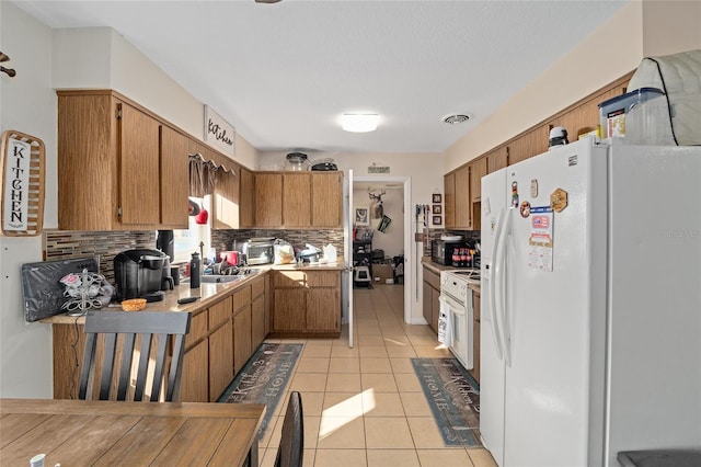 kitchen with white fridge with ice dispenser, light tile patterned floors, a textured ceiling, and decorative backsplash