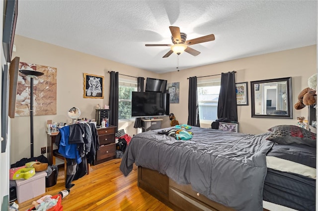 bedroom with multiple windows, ceiling fan, a textured ceiling, and light hardwood / wood-style flooring