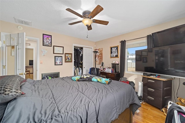 bedroom with a textured ceiling, a closet, ceiling fan, and light wood-type flooring