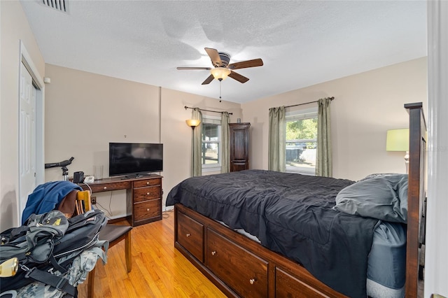 bedroom with ceiling fan, light hardwood / wood-style flooring, and a textured ceiling