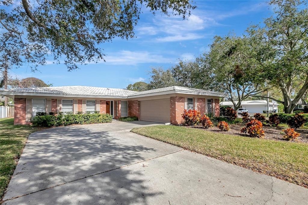 single story home featuring a garage and a front lawn