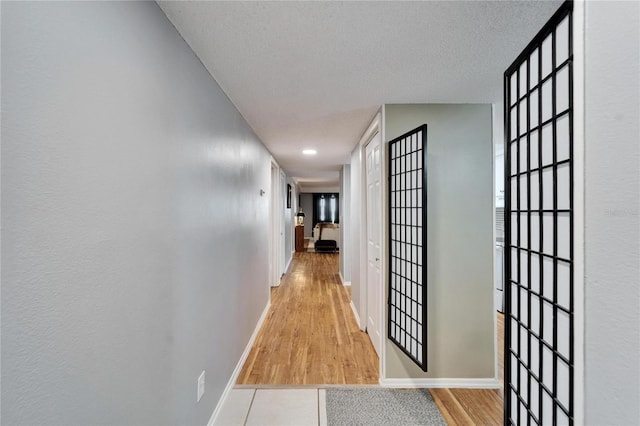 hall with a textured ceiling and light hardwood / wood-style floors