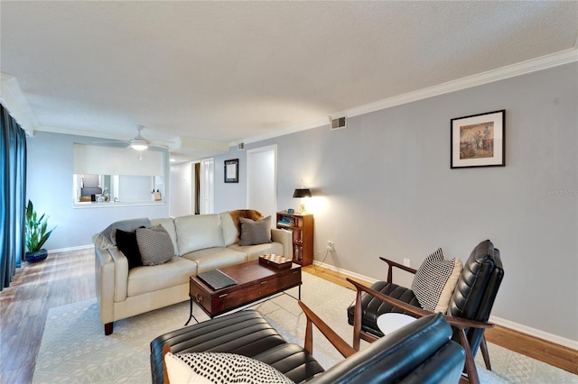 living room with ornamental molding, ceiling fan, and light wood-type flooring