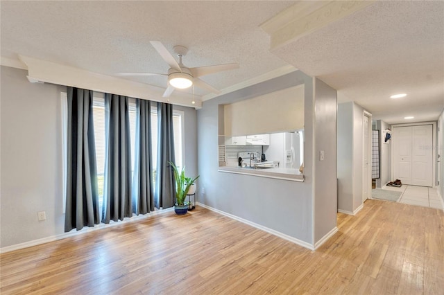 unfurnished room with ceiling fan, light hardwood / wood-style floors, and a textured ceiling