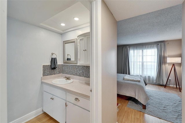 bathroom with vanity, hardwood / wood-style floors, a textured ceiling, and decorative backsplash