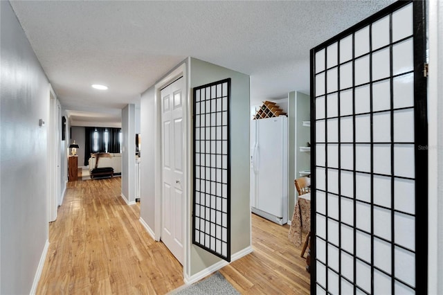 hall featuring a textured ceiling and light hardwood / wood-style flooring