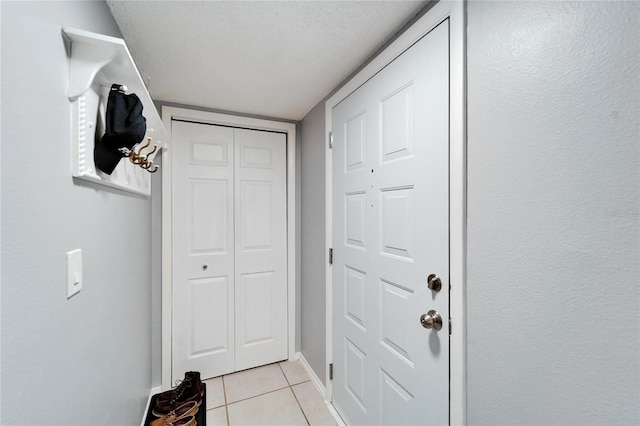 doorway featuring light tile patterned floors and a textured ceiling