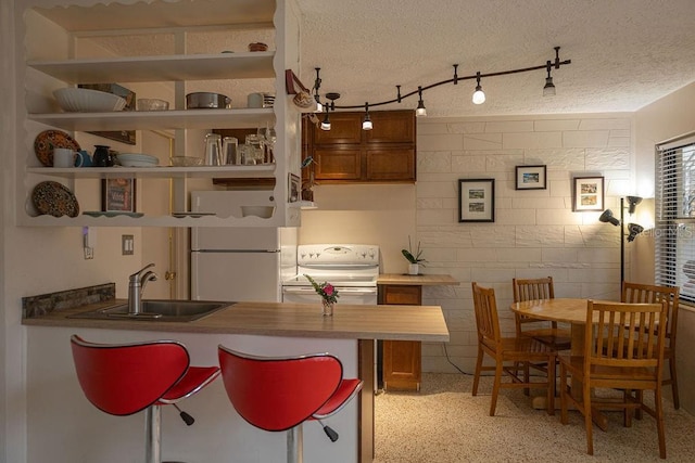 kitchen with sink, white appliances, and a textured ceiling