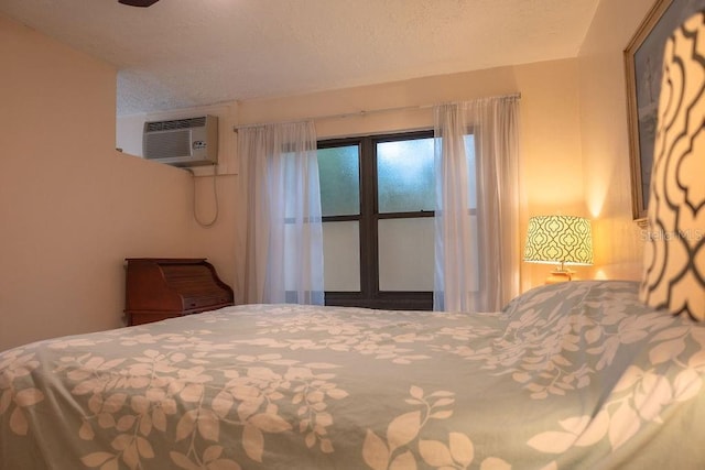 bedroom with a wall mounted AC and a textured ceiling