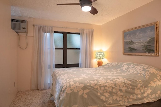 bedroom featuring ceiling fan, an AC wall unit, and a textured ceiling