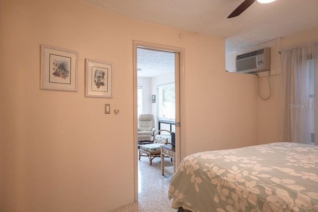 bedroom with ceiling fan, a wall unit AC, and a textured ceiling