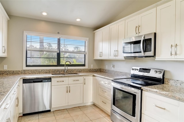 kitchen featuring sink, light stone counters, light tile patterned floors, stainless steel appliances, and white cabinets