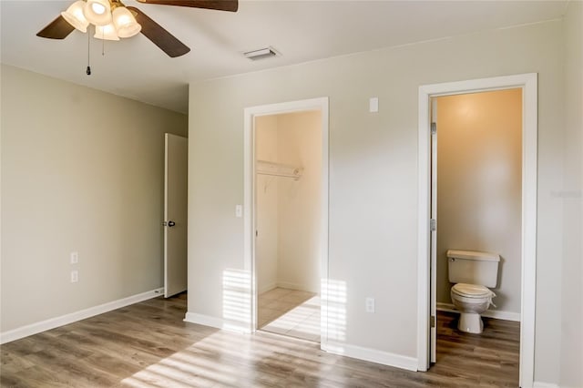 unfurnished bedroom with connected bathroom, hardwood / wood-style flooring, a closet, and a spacious closet