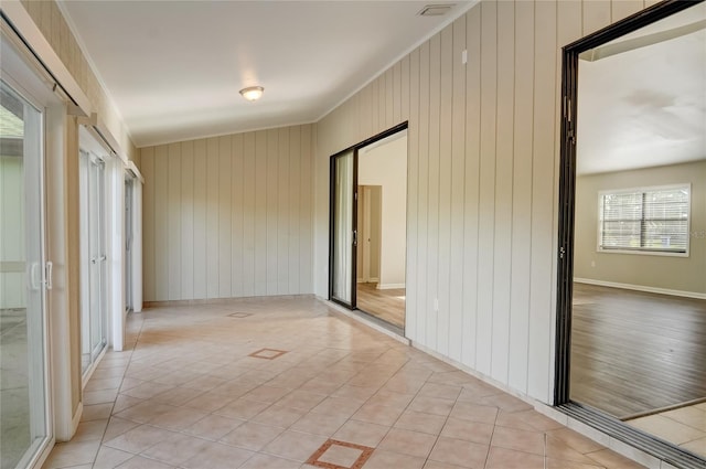 hallway with ornamental molding and light tile patterned floors