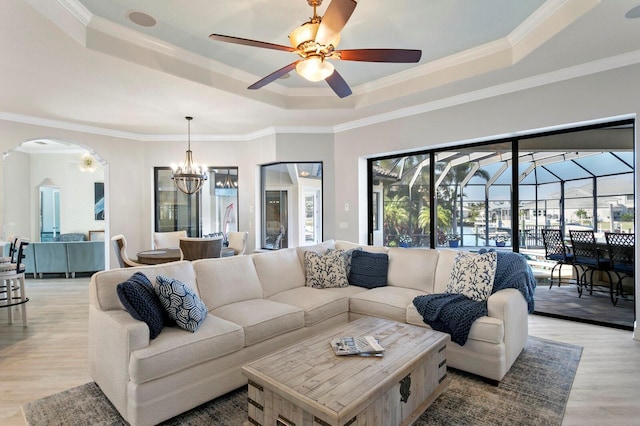 living room with ornamental molding, light hardwood / wood-style flooring, ceiling fan, and a tray ceiling